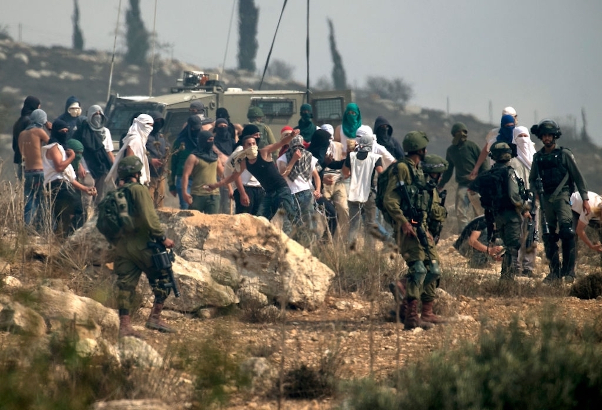 Des colons, gardés par des soldats d'occupation,  prennent d'assaut un village et détiennent un Palestinien