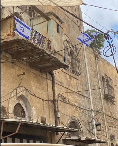 Les colons hissent le drapeau de l’État occupant sur un bâtiment du centre-ville d’Hébron